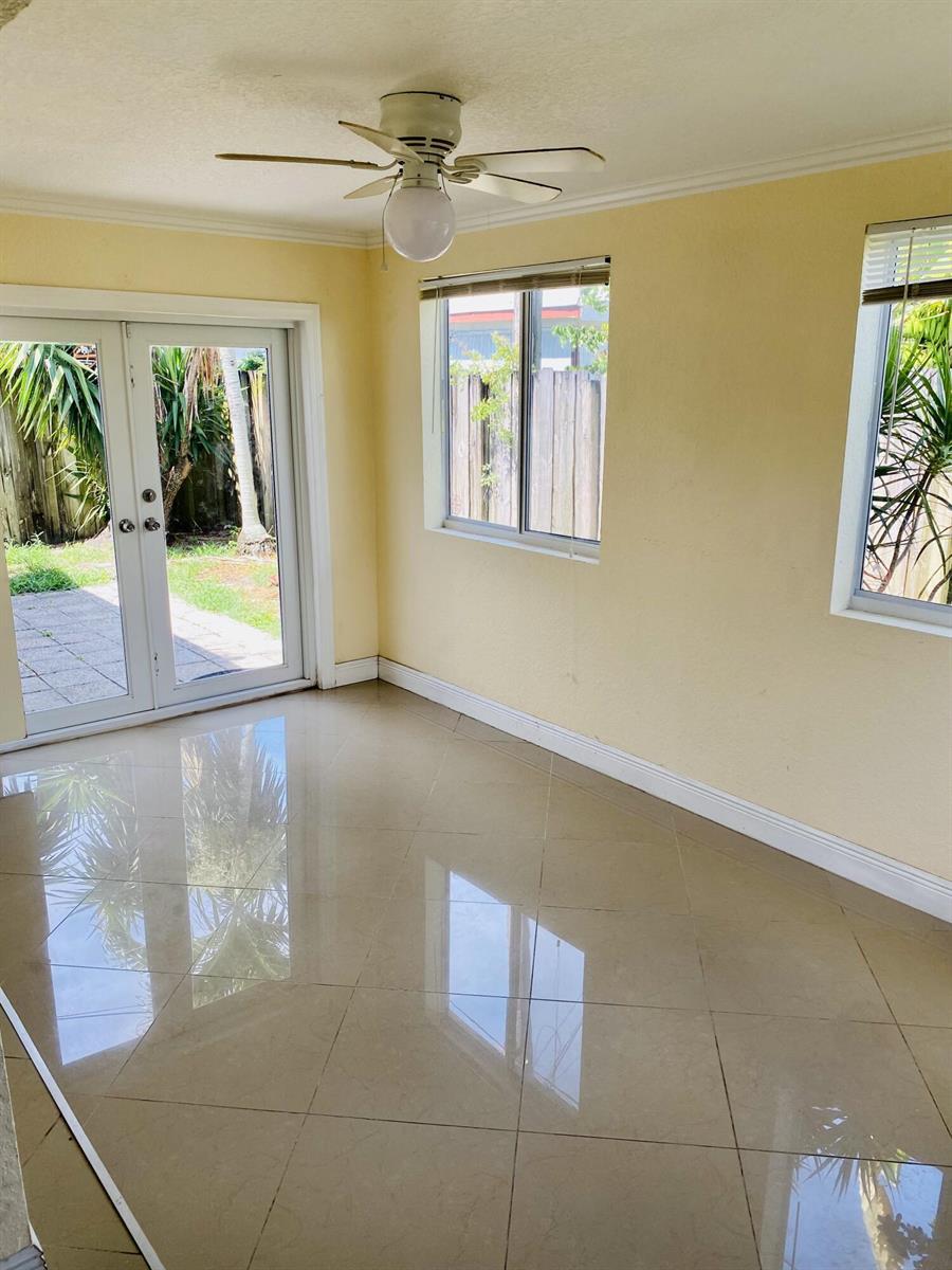 A sunroom with light yellow walls, glossy tile flooring, a ceiling fan, and glass doors — 4559 NW 16th Way, Tamarac FL 33309, TAMARAC, FL