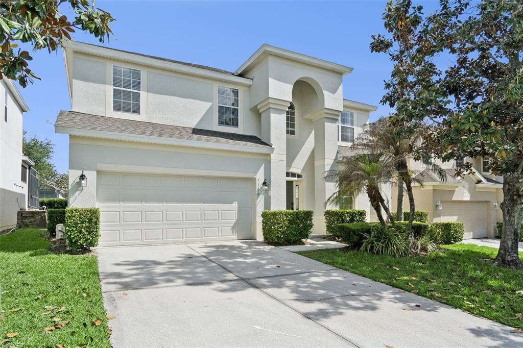 A two-story house with a beige stucco exterior, a two-car garage, and a concrete driveway — 7759 TOSTETH STREET, KISSIMMEE, FL