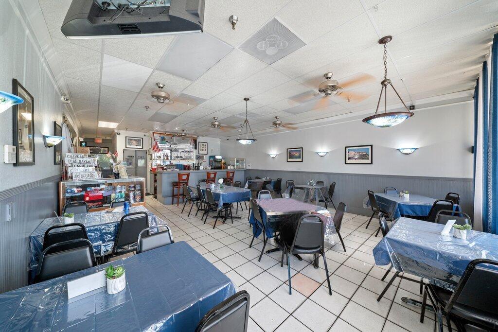 A restaurant dining room features tiled floors, multiple tables with blue covers, and ceiling fans — 3092 S Jog Road, FL 33463, FL
