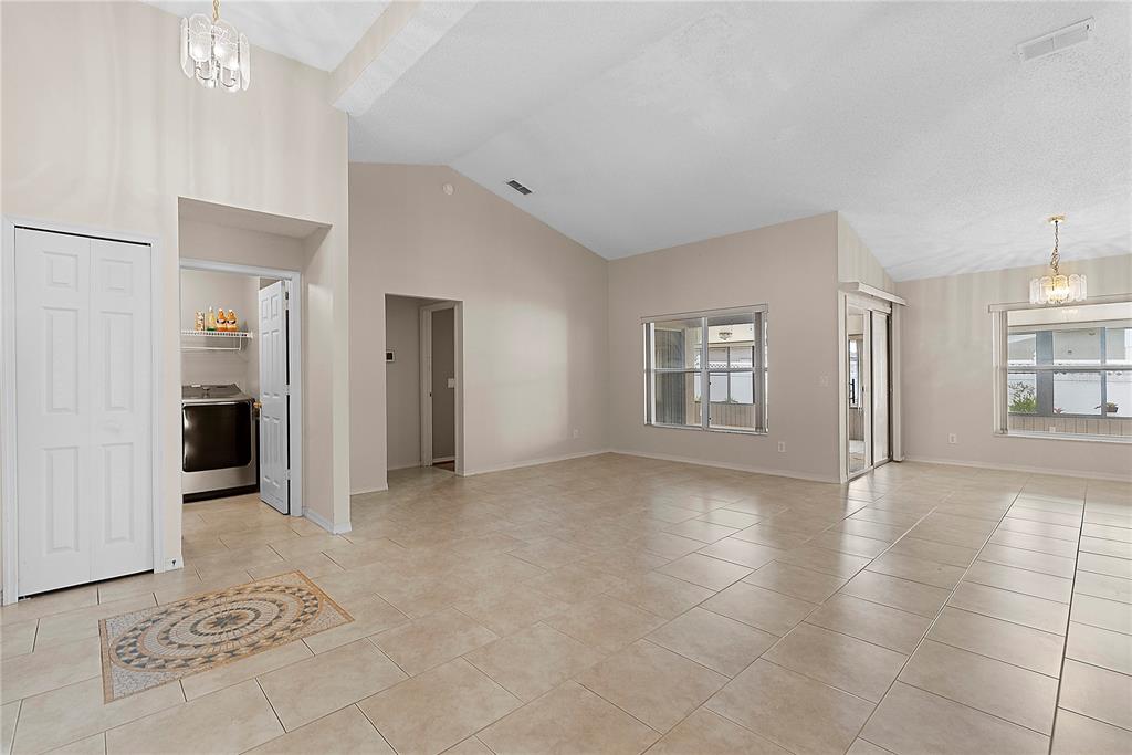 An open-concept living area features vaulted ceilings, light-colored tile flooring, and a laundry closet — 4441 BEAGLE STREET, ORLANDO, FL