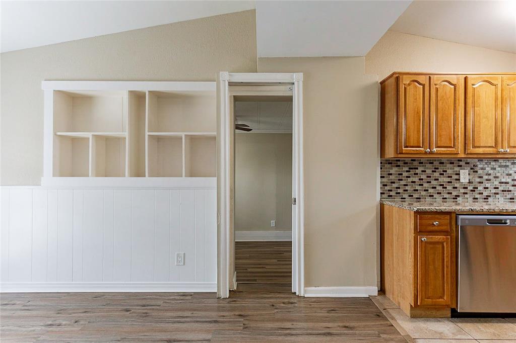 A room features wood-look flooring, white built-in shelving, a doorway, and wooden kitchen cabinets — 7216 E EMMA STREET, TAMPA, FL