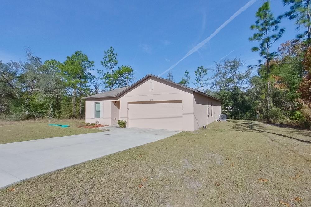 A single-story house with a beige stucco exterior, a two-car garage, and a concrete driveway — 2799 W SHEILA DRIVE, CITRUS SPRINGS, FL