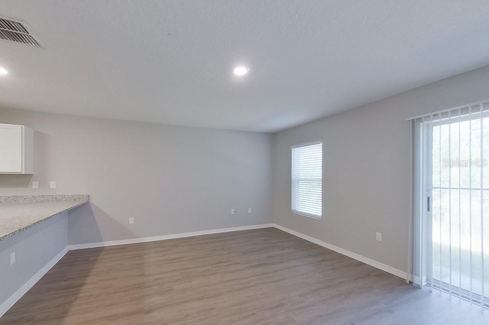 An empty living room features light gray walls, wood-look flooring, a window, and sliding doors — 2799 W SHEILA DRIVE, CITRUS SPRINGS, FL