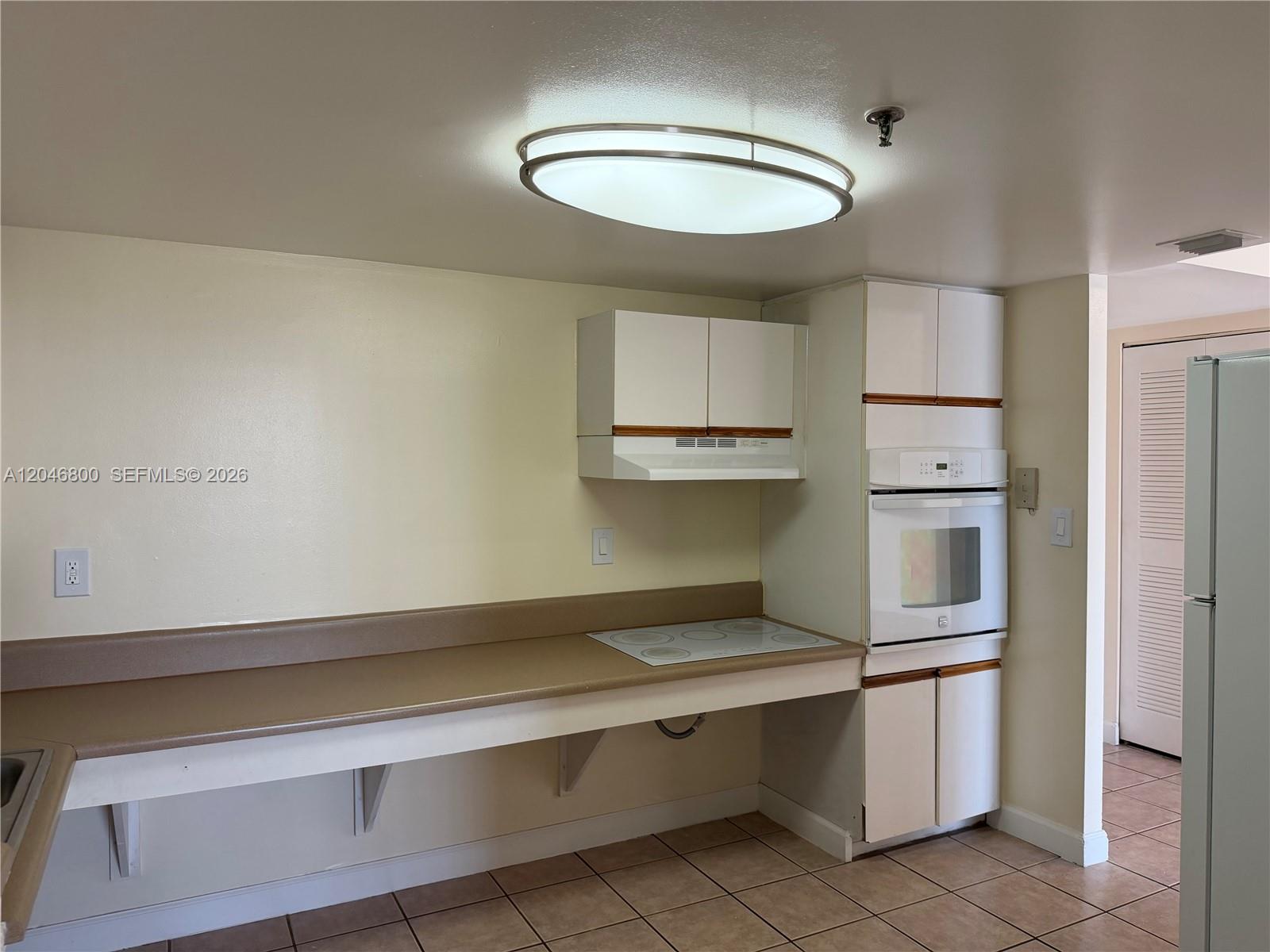 A kitchen features white cabinetry, a built-in oven, a cooktop, and a long countertop — 915 NW 1st Ave # H2707, Miami FL 33136, MIAMI, FL