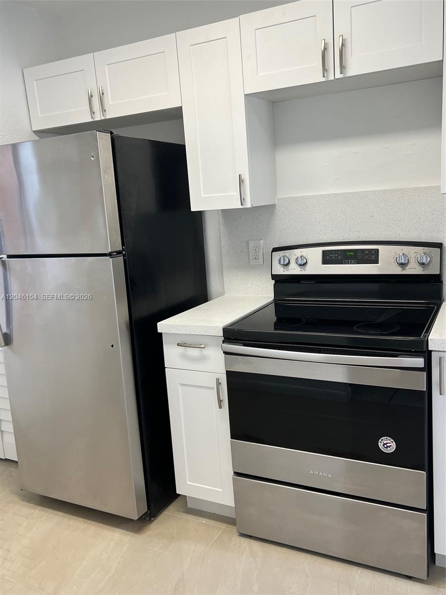 A kitchen features white cabinets, stainless steel appliances, and light-colored countertops — 852 NE 209th St # 38, Miami FL 33179, MIAMI, FL