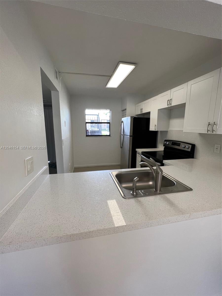 A kitchen features white cabinets, light-colored countertops, a stainless steel sink, and stainless steel appliances — 852 NE 209th St # 38, Miami FL 33179, MIAMI, FL