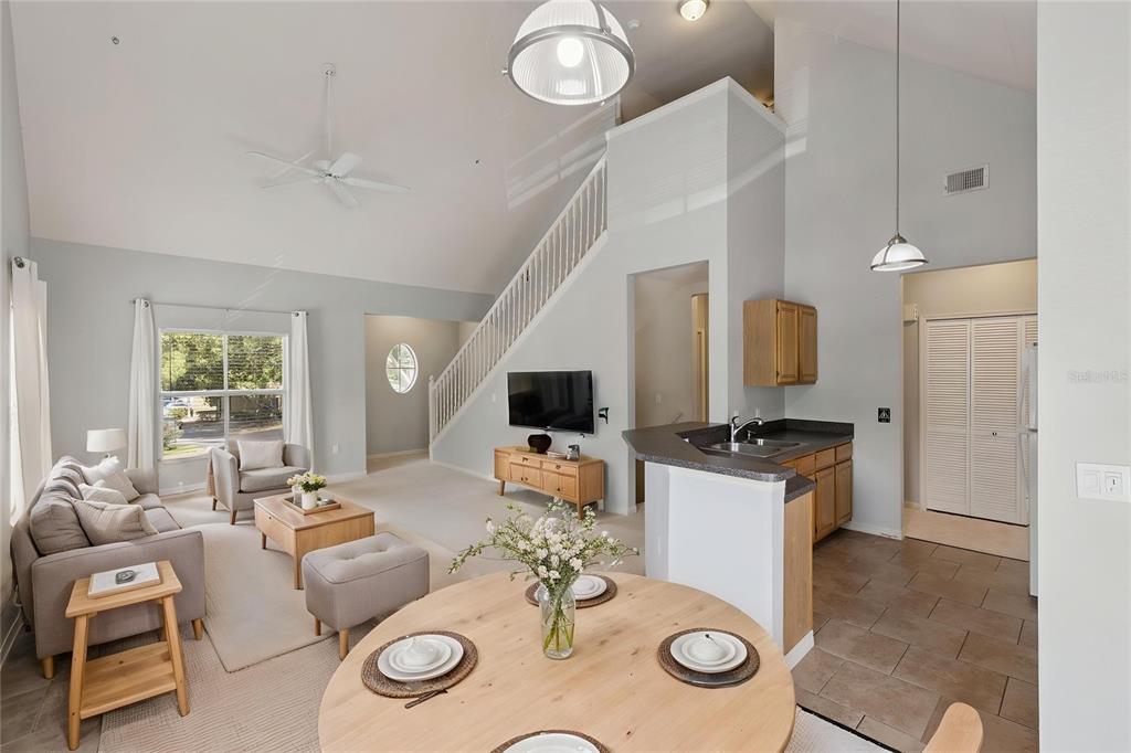 An open-concept living room and kitchen with vaulted ceilings, a staircase, and light-colored walls — 5959 WESTGATE DRIVE UNIT 1527, ORLANDO, FL