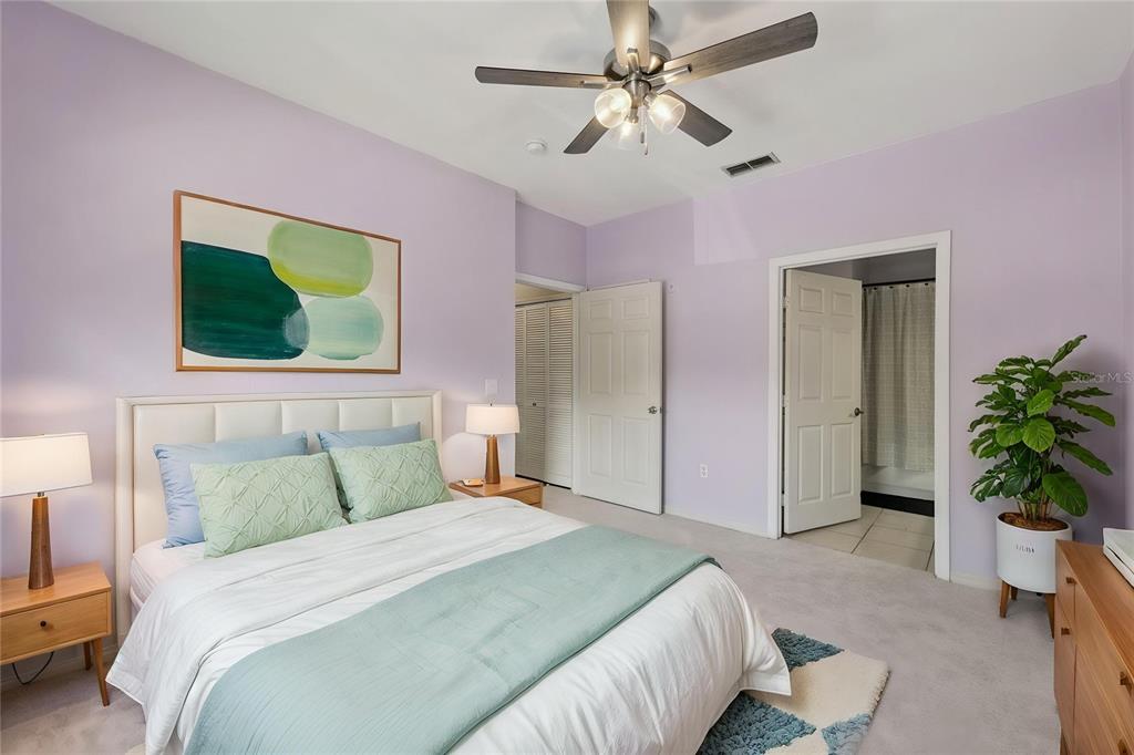 A bedroom features light purple walls, a queen bed, a ceiling fan, and an ensuite bathroom — 5959 WESTGATE DRIVE UNIT 1527, ORLANDO, FL