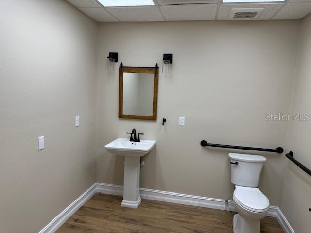 A bathroom features a pedestal sink, a mirror, and a toilet with black grab bars — 228 NEW YORK AVENUE E UNIT C, DELAND, FL