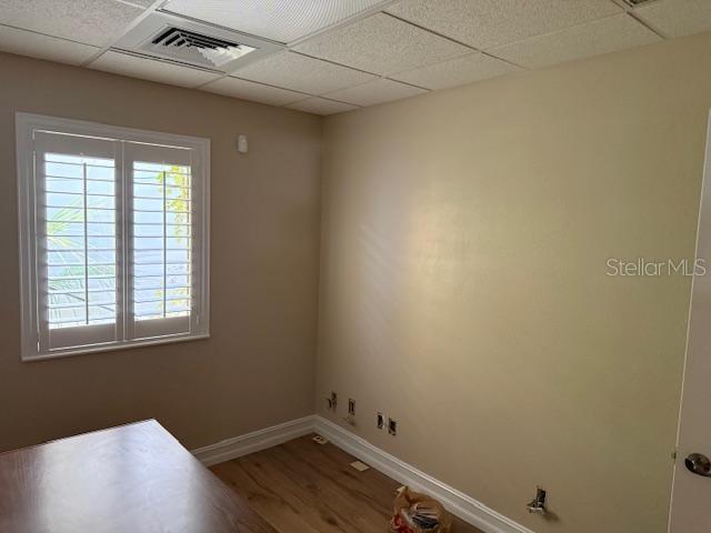 An office with light-colored walls, wood-look flooring, a window with shutters, and a drop ceiling — 228 NEW YORK AVENUE E UNIT C, DELAND, FL