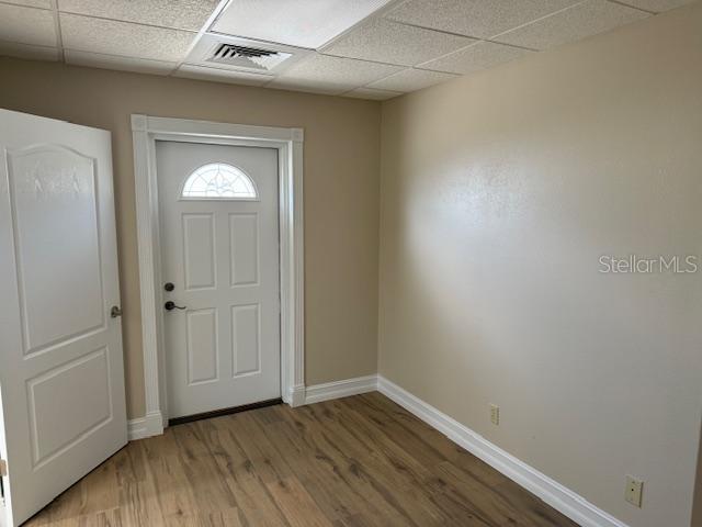 An interior room features light-colored walls, wood-look flooring, a white door, and a drop ceiling — 228 NEW YORK AVENUE E UNIT C, DELAND, FL