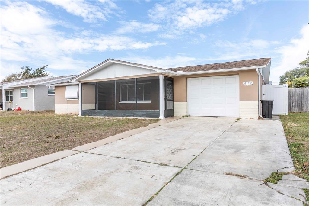 A single-story house with a screened-in front porch, a one-car garage, and a concrete driveway — 6149 2ND AVENUE, NEW PORT RICHEY, FL
