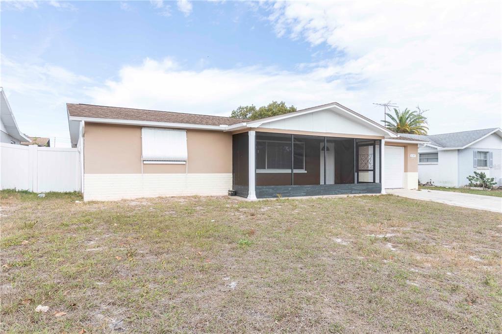 A single-story house with a tan exterior, a screened-in front porch, and a white garage — 6149 2ND AVENUE, NEW PORT RICHEY, FL