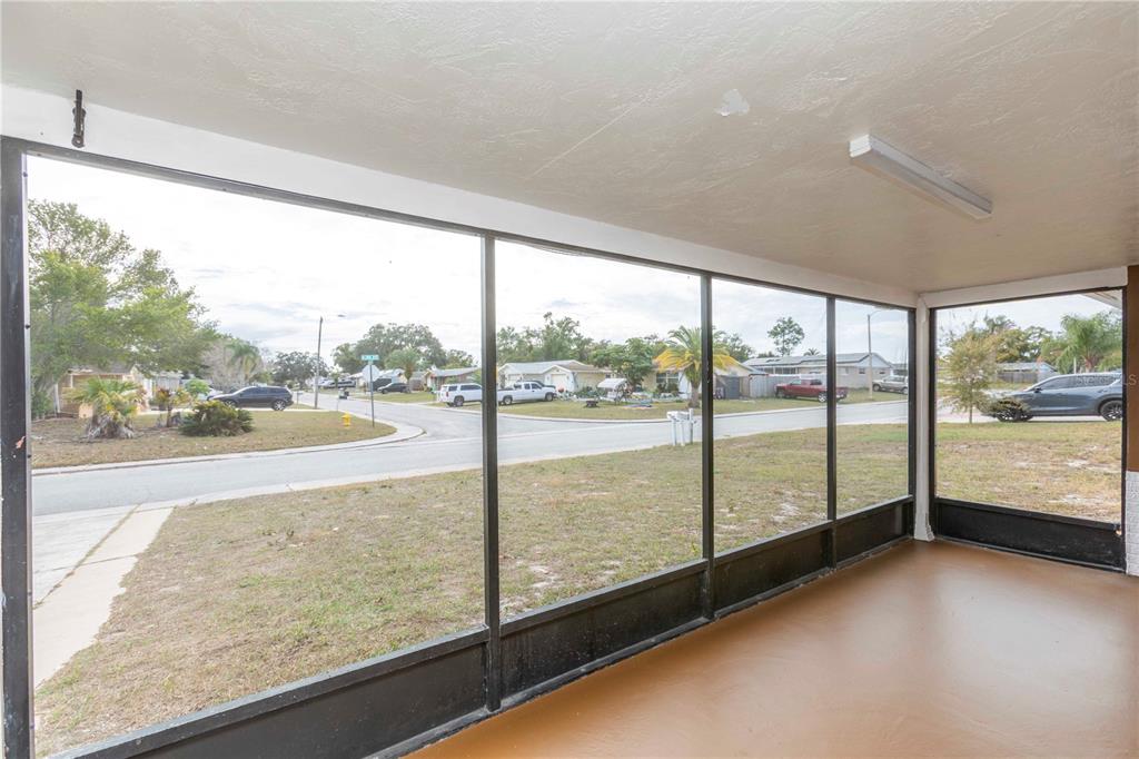 A screened-in porch with a painted concrete floor overlooks a residential street — 6149 2ND AVENUE, NEW PORT RICHEY, FL