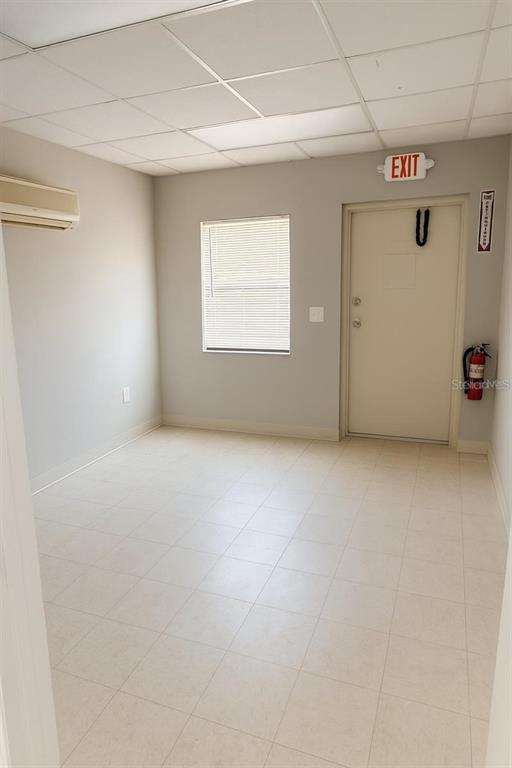 A small, empty room with light-colored tile flooring, a window with blinds, and an exit door — 4500 NE 35 STREET, OCALA, FL