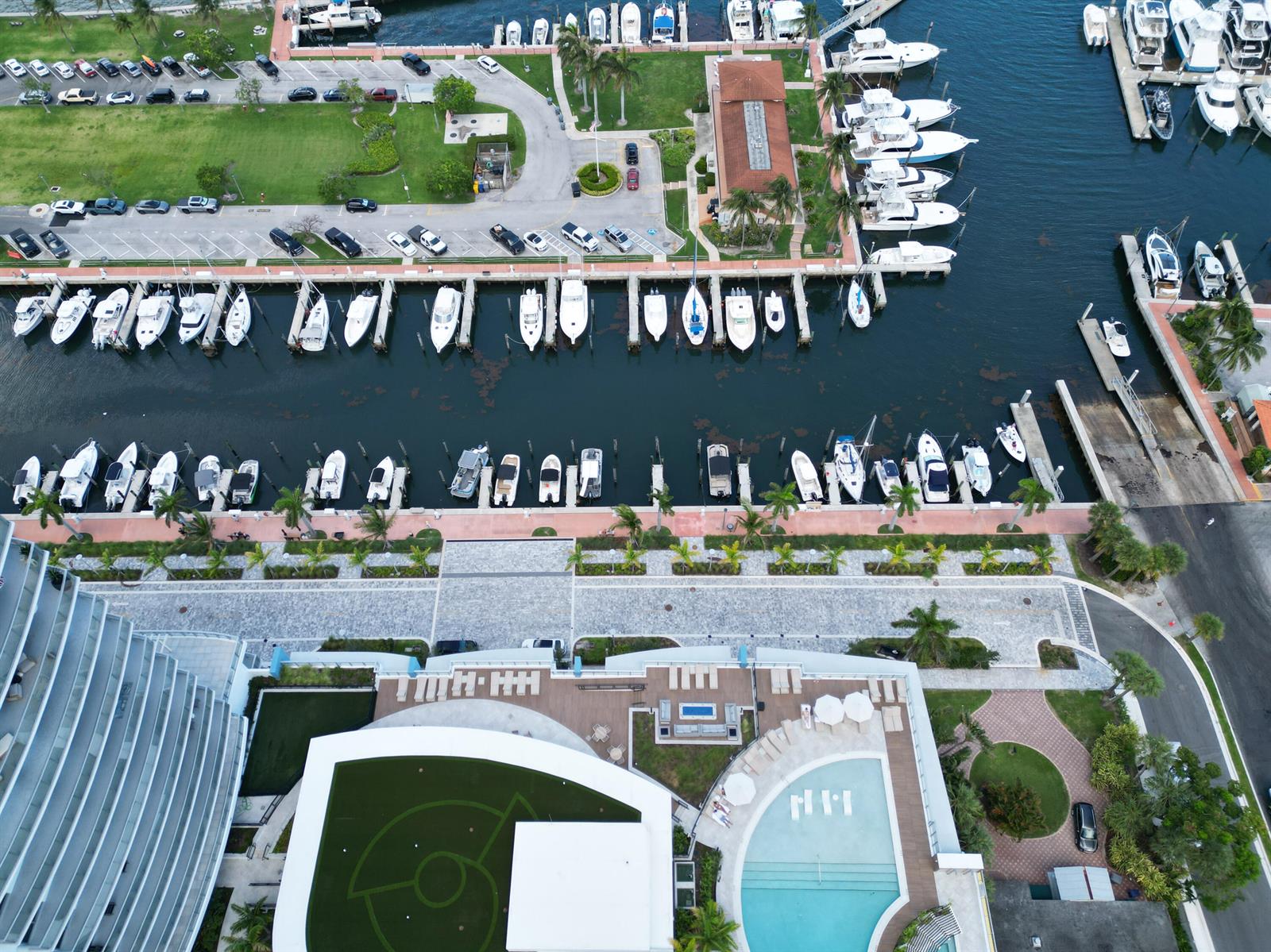 An aerial view shows a marina with numerous docked boats beside a modern residential building — 220 Lake Shore Drive # 1908, Lake Park FL 33403, LAKE PARK, FL