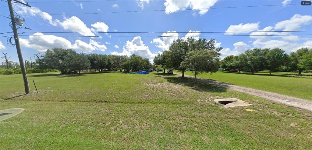 A large, grassy vacant lot features scattered trees, a utility pole, and a drainage culvert — TIGER LAKE RD, LAKE WALES, FL