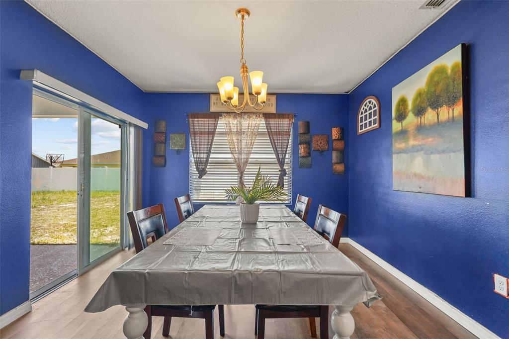 A dining room with blue walls, a long table, and a sliding glass door — 931 SUMMER GLEN DRIVE, WINTER HAVEN, FL