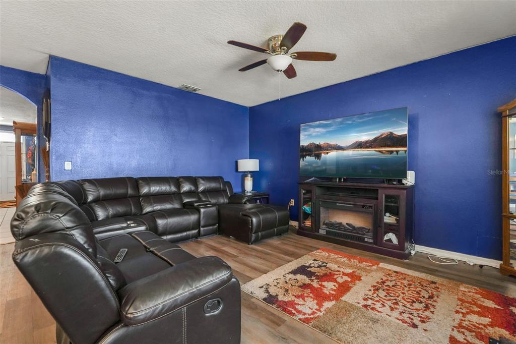 A living room features blue walls, a large sectional sofa, a television, and a fireplace console — 931 SUMMER GLEN DRIVE, WINTER HAVEN, FL