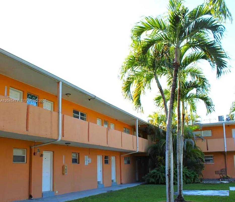 An exterior view of a two-story orange apartment building with a palm tree — 9760 SW 184th St # 12D, Cutler Bay FL 33157, CUTLER BAY, FL