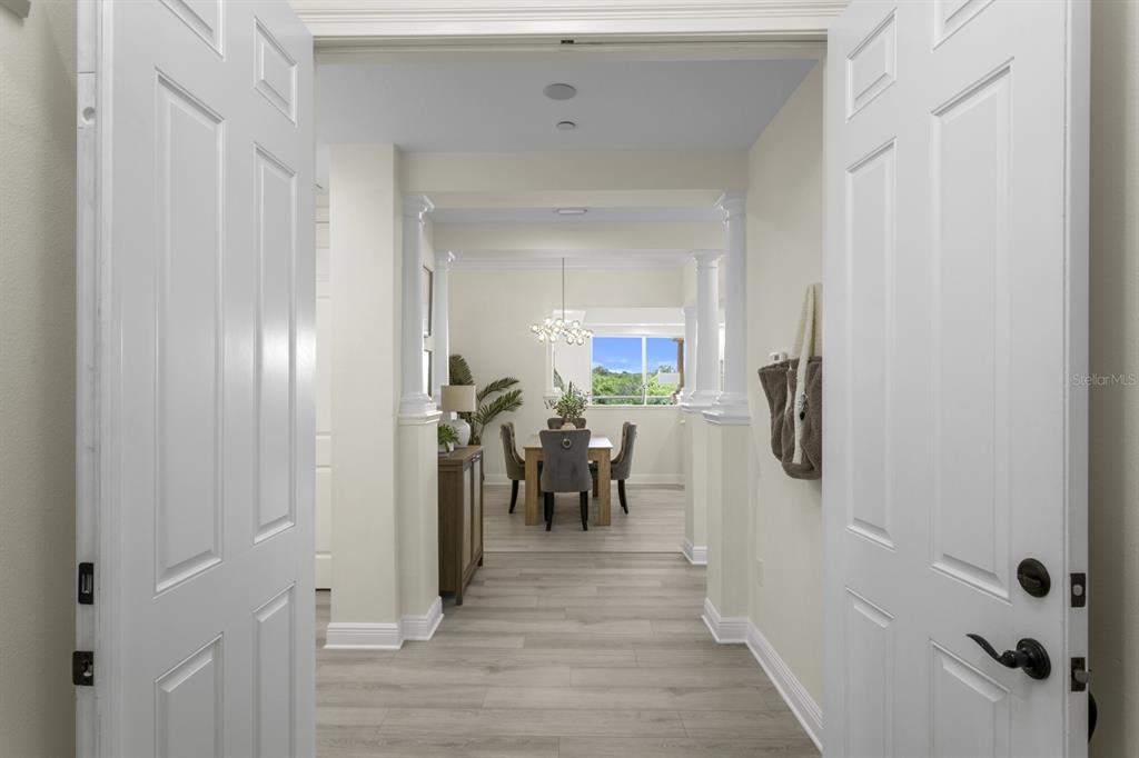 A view through double doors into a dining room with columns and light wood flooring — 43 BAYVIEW COURT S UNIT A, ST PETERSBURG, FL