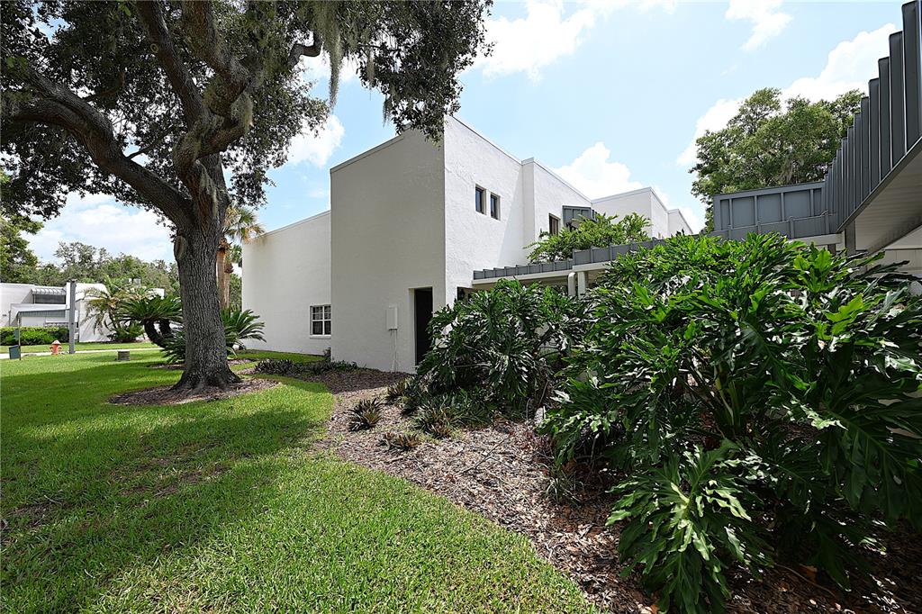 A white multi-story building with a large oak tree and lush landscaping in the foreground — 1808 VILLAGE COURT, MULBERRY, FL