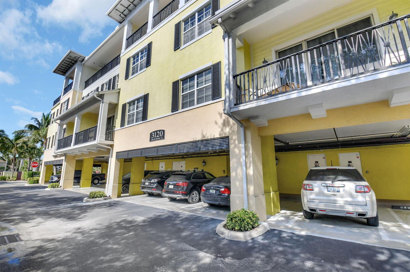 A yellow multi-story apartment building with covered ground-level parking and balconies — 3120 E Latitude Circle # 307, Delray Beach FL 33483, DELRAY BEACH, FL