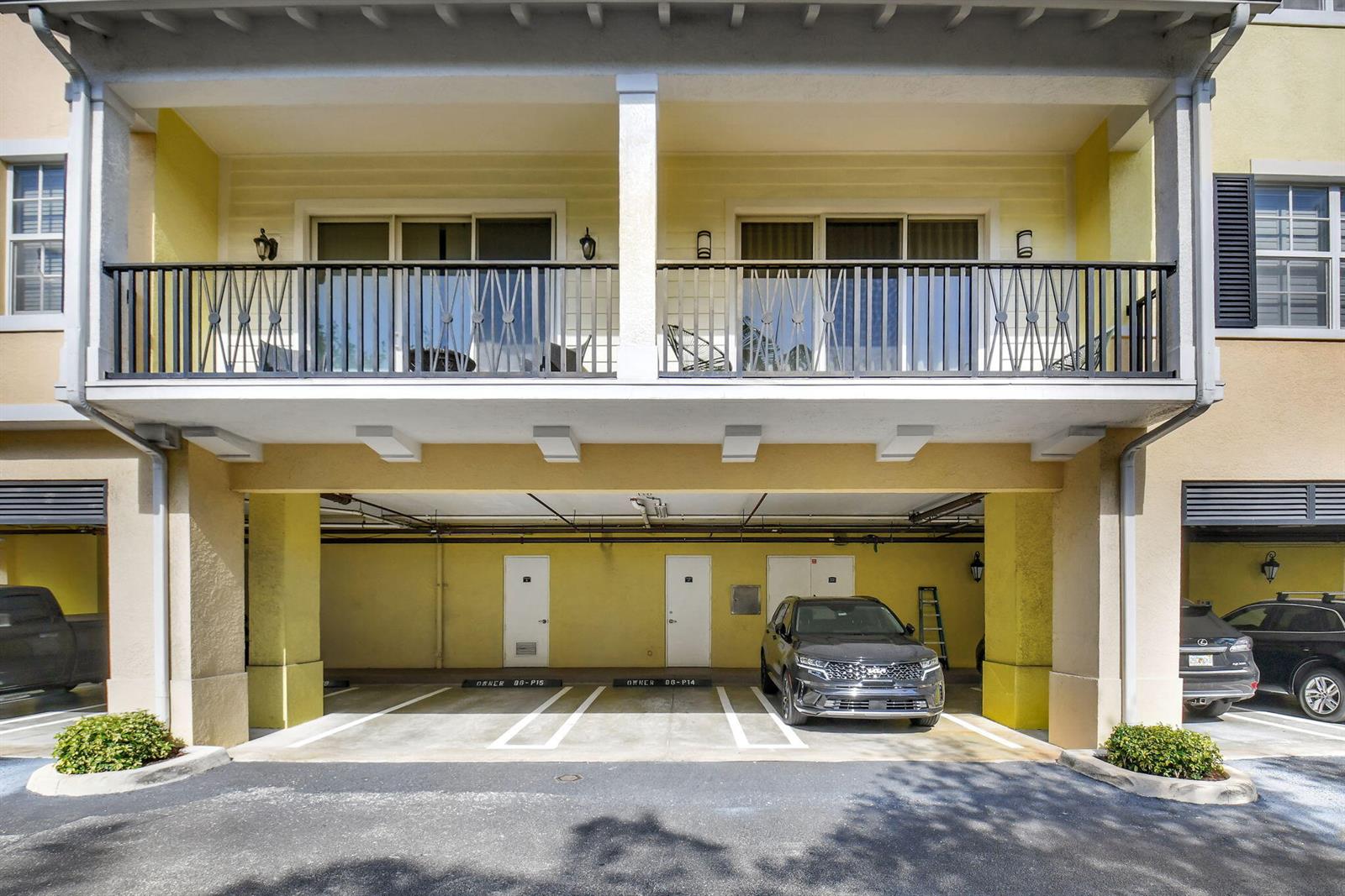 A two-story building exterior features a covered ground-level parking area beneath a balcony with railings — 3120 E Latitude Circle # 307, Delray Beach FL 33483, DELRAY BEACH, FL