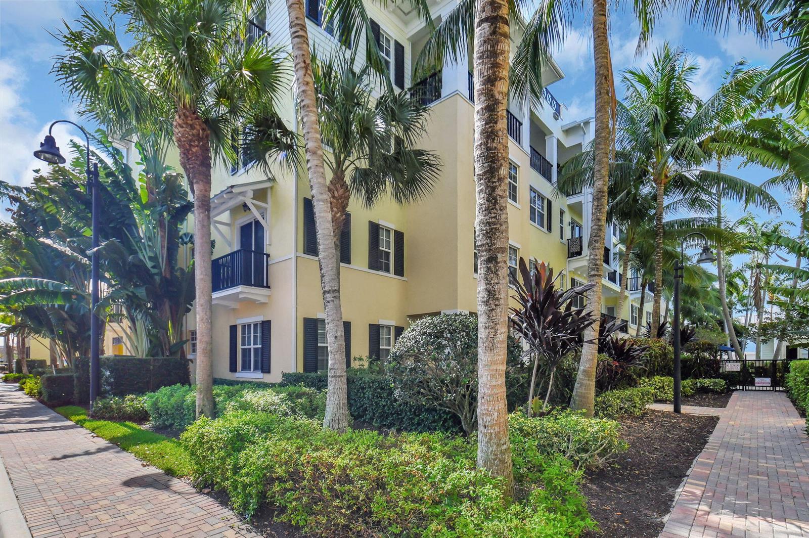 A multi-story yellow apartment building with balconies is surrounded by palm trees and landscaping — 3120 E Latitude Circle # 307, Delray Beach FL 33483, DELRAY BEACH, FL