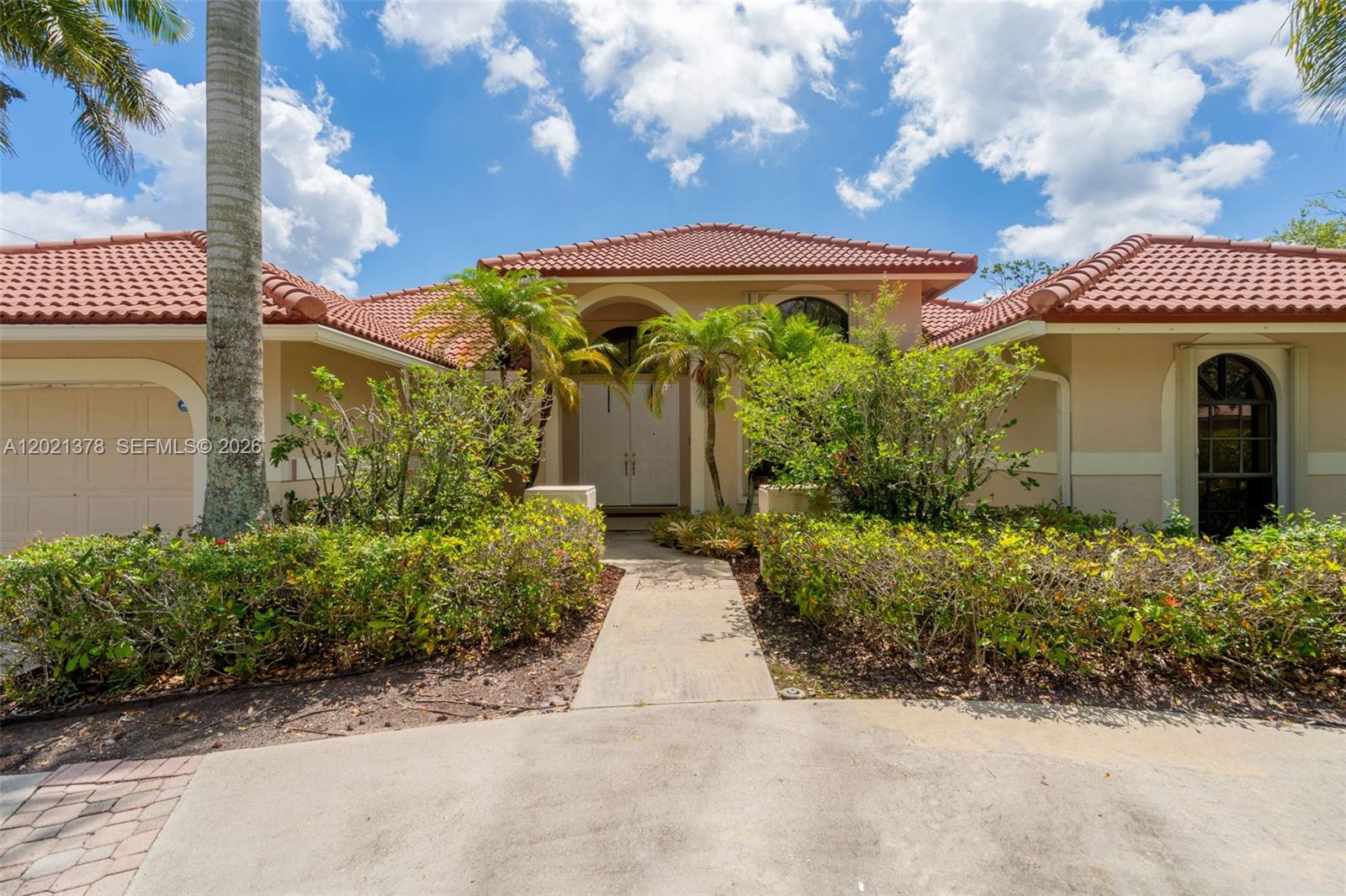 A single-story house with a red tile roof, beige stucco walls, and a landscaped walkway — 1051 Deerpath Ct, Weston FL 33326, WESTON, FL