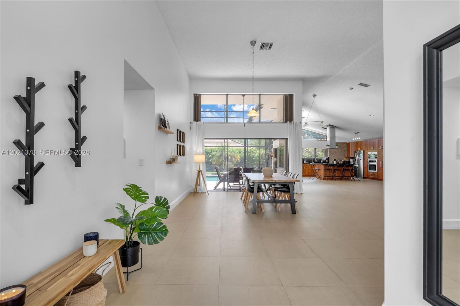 An open-concept dining area features tile flooring, high ceilings, and a view of the pool — 1051 Deerpath Ct, Weston FL 33326, WESTON, FL
