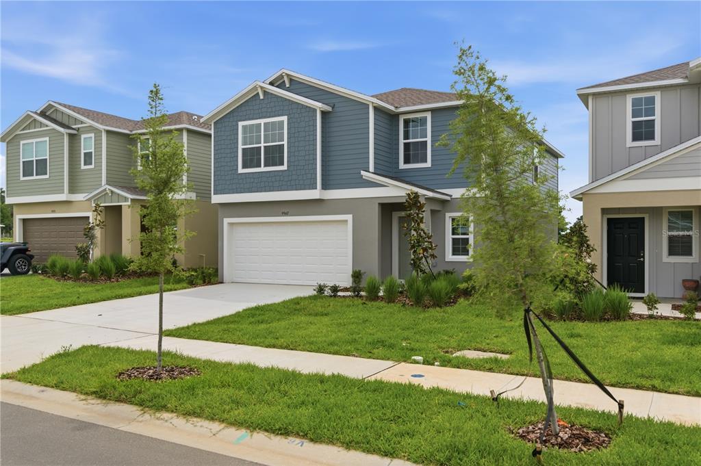 A two-story blue and gray suburban house with a white garage and front lawn — 9947 ALLENDALE ST STREET, WESLEY CHAPEL, FL