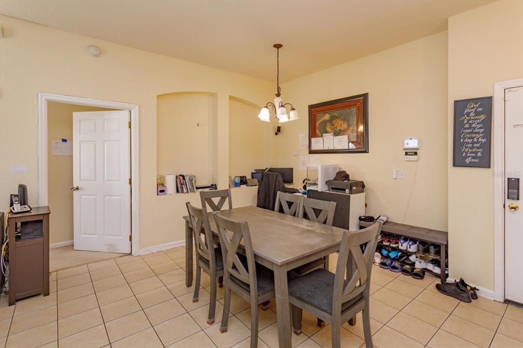 A dining room features a gray wooden table and chairs on a tiled floor — 3001 LAUREL RUN LANE UNIT 206, KISSIMMEE, FL
