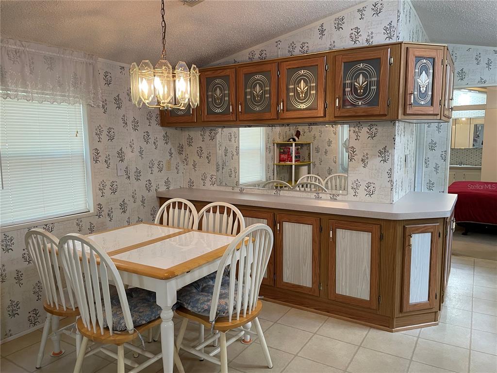 A dining area features a white table with chairs, wood cabinetry, and patterned wallpaper — 8089 SW 147TH LANE, DUNNELLON, FL