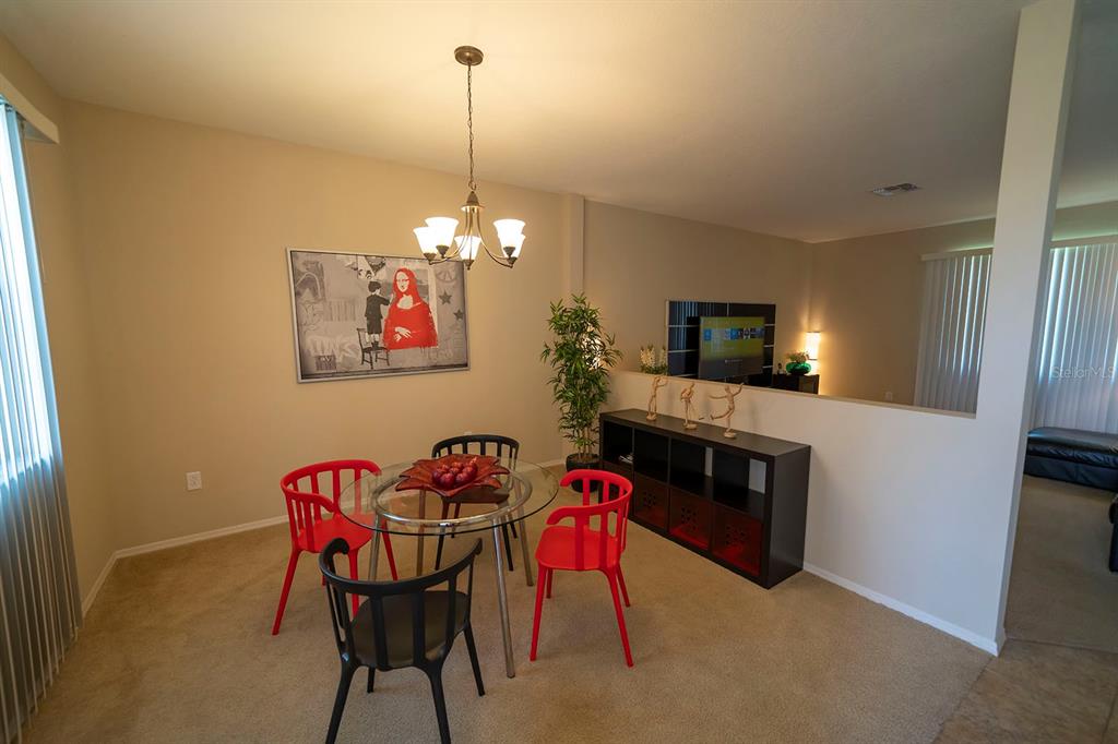 A dining area features a glass table, red and black chairs, and a wall-mounted television — 1039 TOURMALINE DRIVE, KISSIMMEE, FL