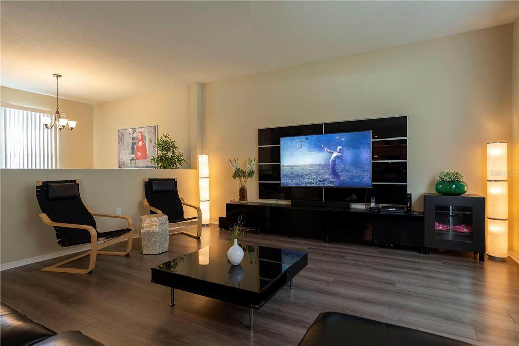 A modern living room features dark wood flooring, a black media console, and two armchairs — 1039 TOURMALINE DRIVE, KISSIMMEE, FL