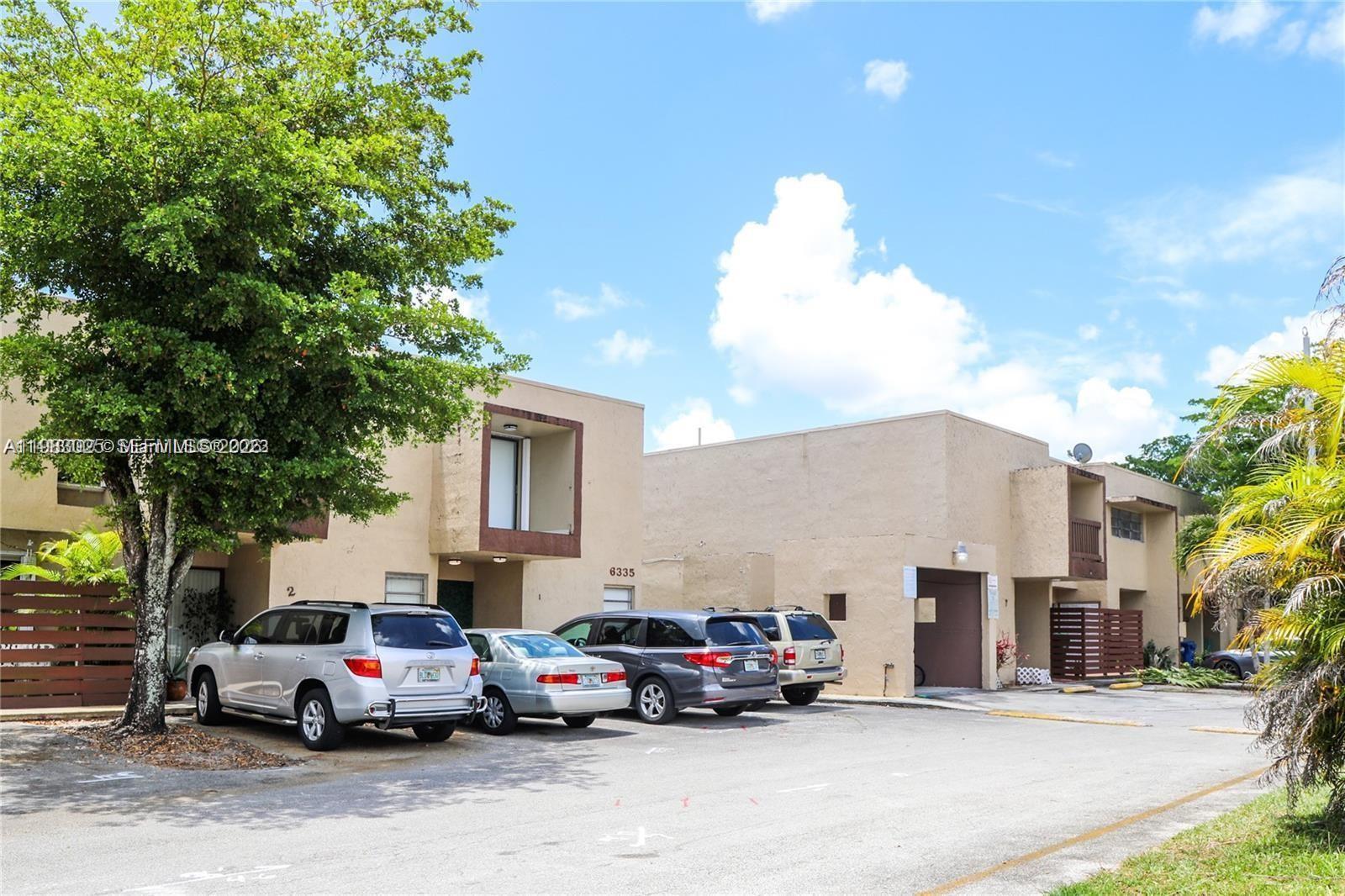 A two-story tan apartment building features a parking lot with several parked cars — 6335 SW 138th Ct # 1, Miami FL 33183, MIAMI, FL
