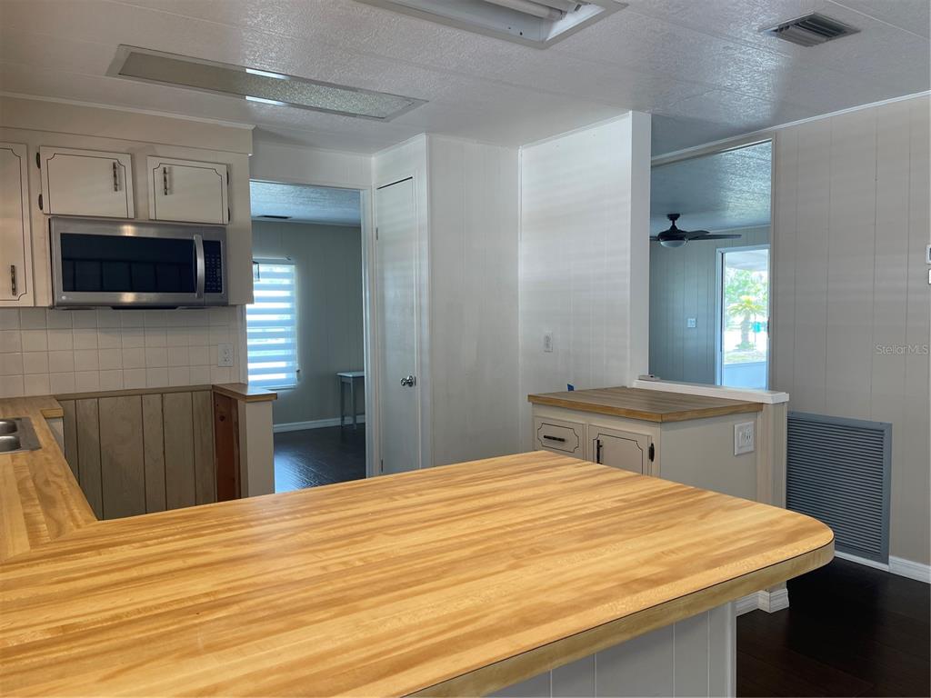 A kitchen features light-colored cabinets, a butcher block countertop, and a built-in microwave — 52 N BOBWHITE RD, WILDWOOD, FL