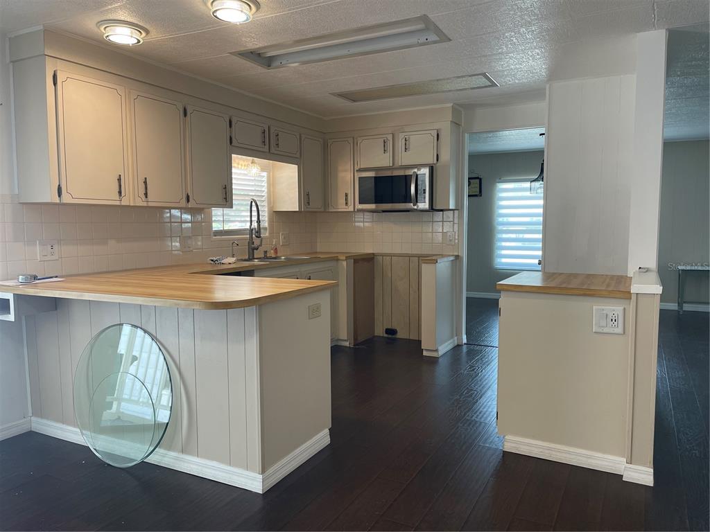 A kitchen features light-colored cabinets, a wood countertop, and dark wood-look flooring — 52 N BOBWHITE RD, WILDWOOD, FL