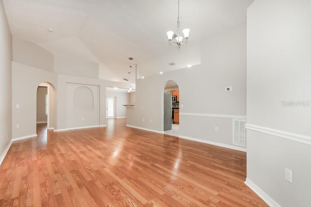 An open-concept living area features light gray walls, hardwood flooring, and arched doorways — 1309 ALHAMBRA CREST DRIVE, RUSKIN, FL