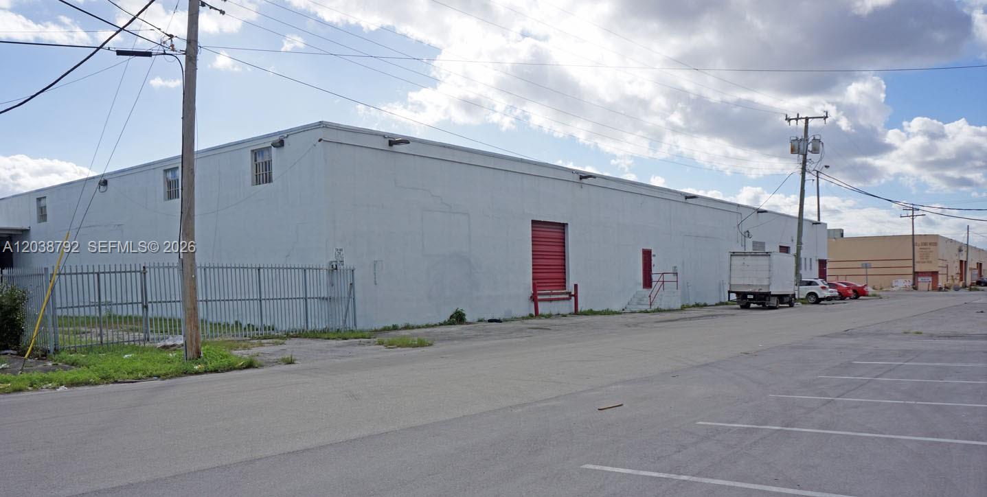 A large, white industrial warehouse building features a red roll-up door and a loading dock — 3690 NW 52nd St, Hialeah FL 33142, HIALEAH, FL