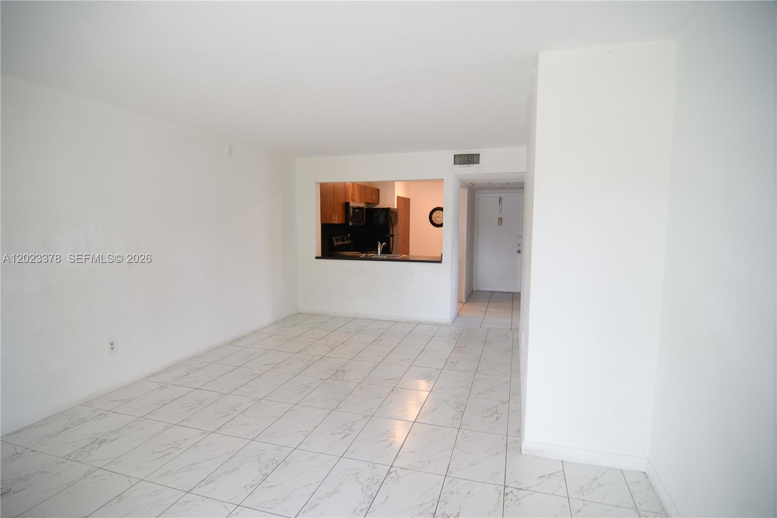 An empty room with white marble-patterned tile flooring and a pass-through kitchen window — 20825 NE 8th Ct # 19, Miami FL 33179, MIAMI, FL