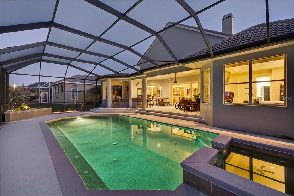 A screened-in patio features a swimming pool, a raised hot tub, and an outdoor kitchen — 5510 E LONGBOAT BOULEVARD, TAMPA, FL