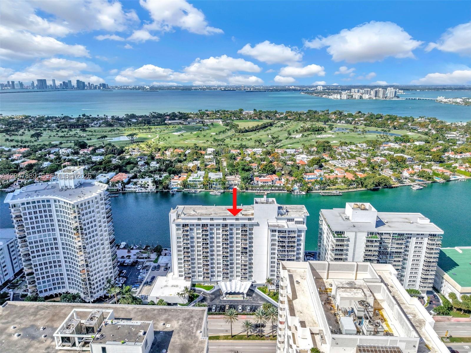 An aerial view shows a multi-story residential building marked with a red arrow near water — 5700 Collins Ave # 6J, Miami Beach FL 33140, MIAMI BEACH, FL