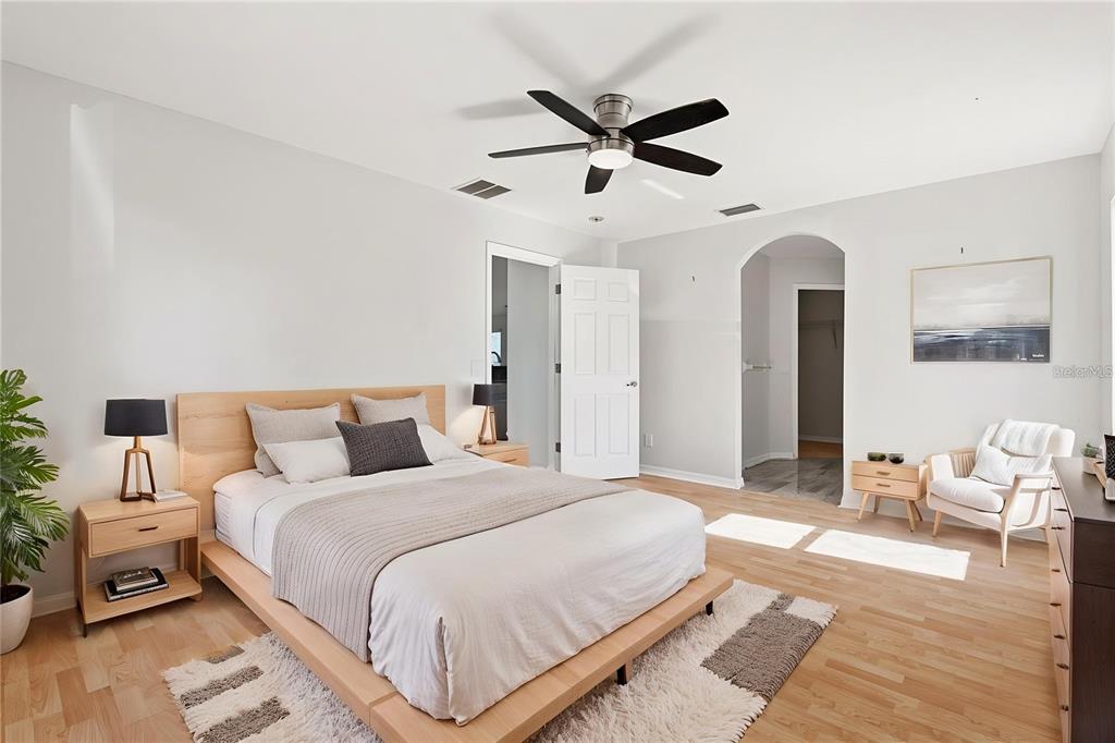A bedroom features a platform bed, a ceiling fan, light wood flooring, and an arched doorway — 4171 MAGENTA AVENUE, NORTH PORT, FL