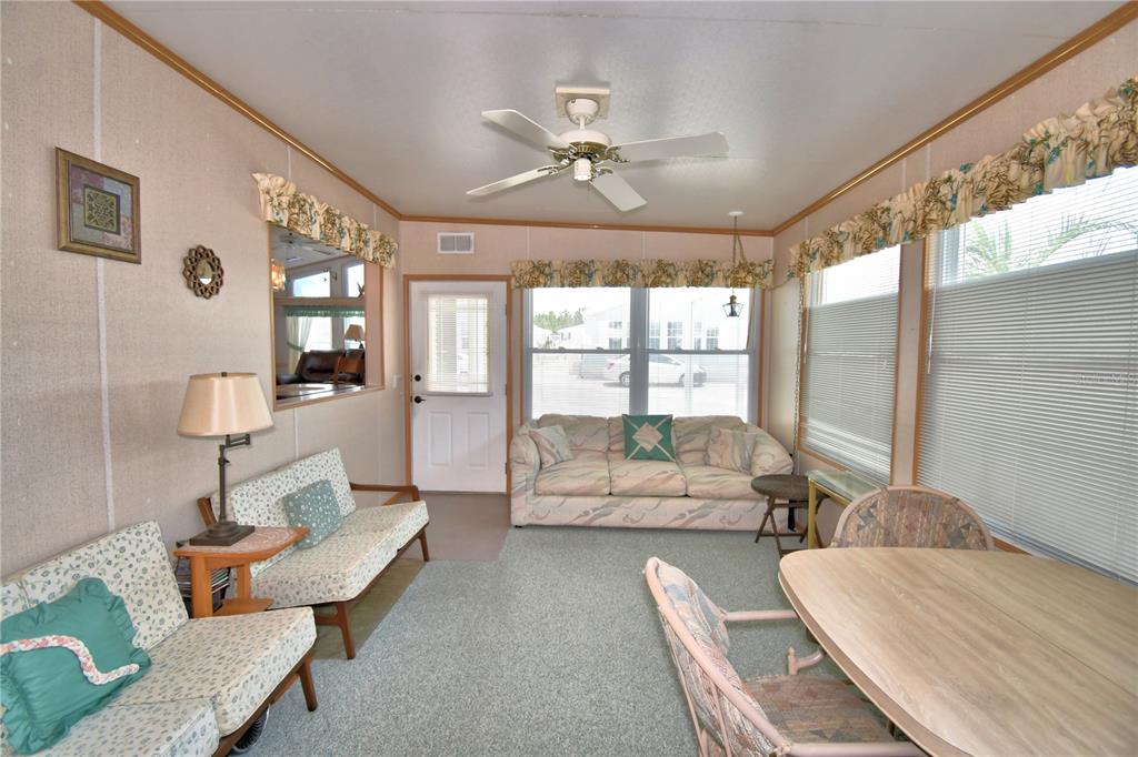A sunroom with a ceiling fan, carpeted flooring, a sofa, and a dining table — 251 PATTERSON ROAD UNIT H38, HAINES CITY, FL