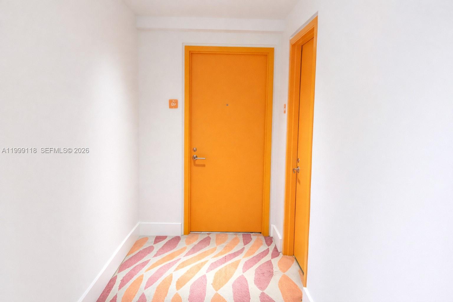 A hallway features white walls, patterned carpet, and two bright orange doors — 31 SE 6th St # 301, Miami FL 33131, MIAMI, FL