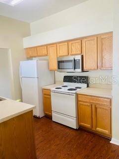 A kitchen features light wood cabinets, white appliances, and wood-look flooring — 7731 MERCHANTVILLE CIRCLE, ZEPHYRHILLS, FL