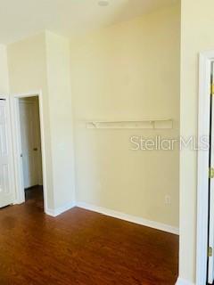 A room with wood-look flooring, a single wall-mounted shelf, and two doorways — 7731 MERCHANTVILLE CIRCLE, ZEPHYRHILLS, FL