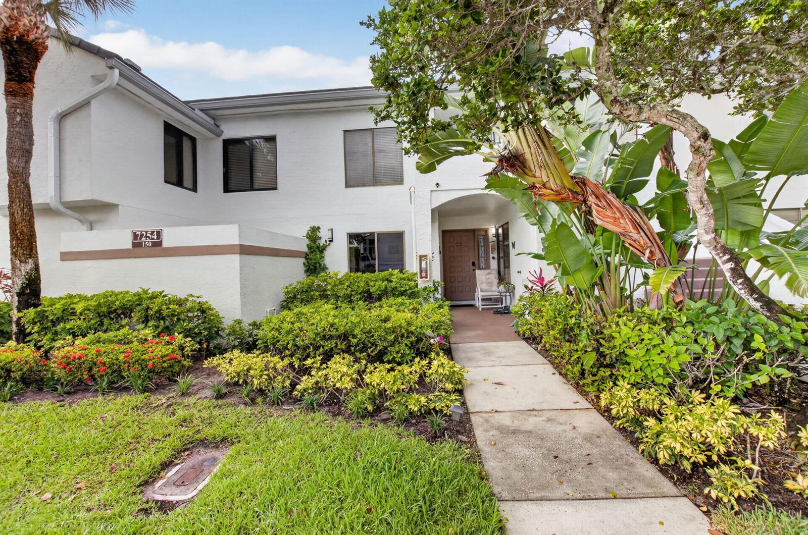 A two-story white stucco building features a walkway leading to a recessed front entrance — 7254 Clunie Place # 15002, Delray Beach FL 33446, DELRAY BEACH, FL